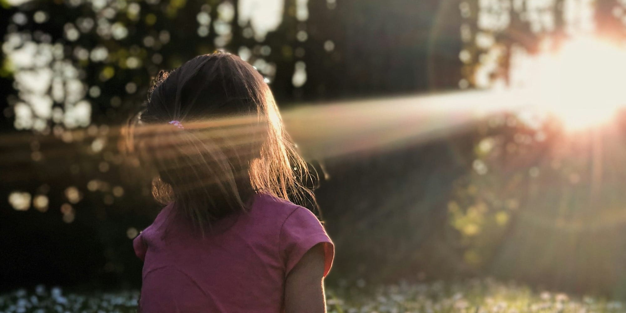 girl sitting on daisy flowerbed in forest